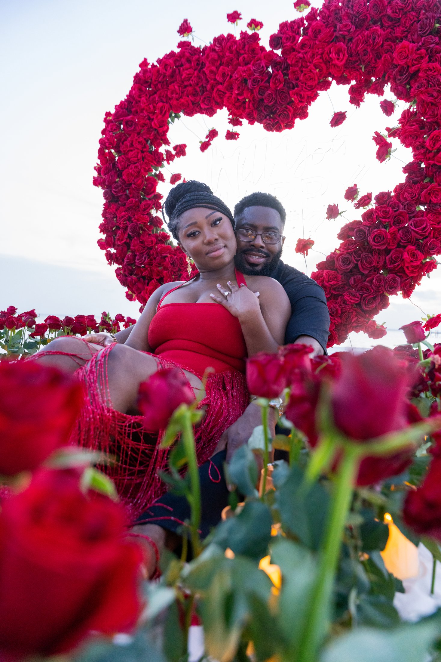 A couple surrounded by an abundant red rose installation