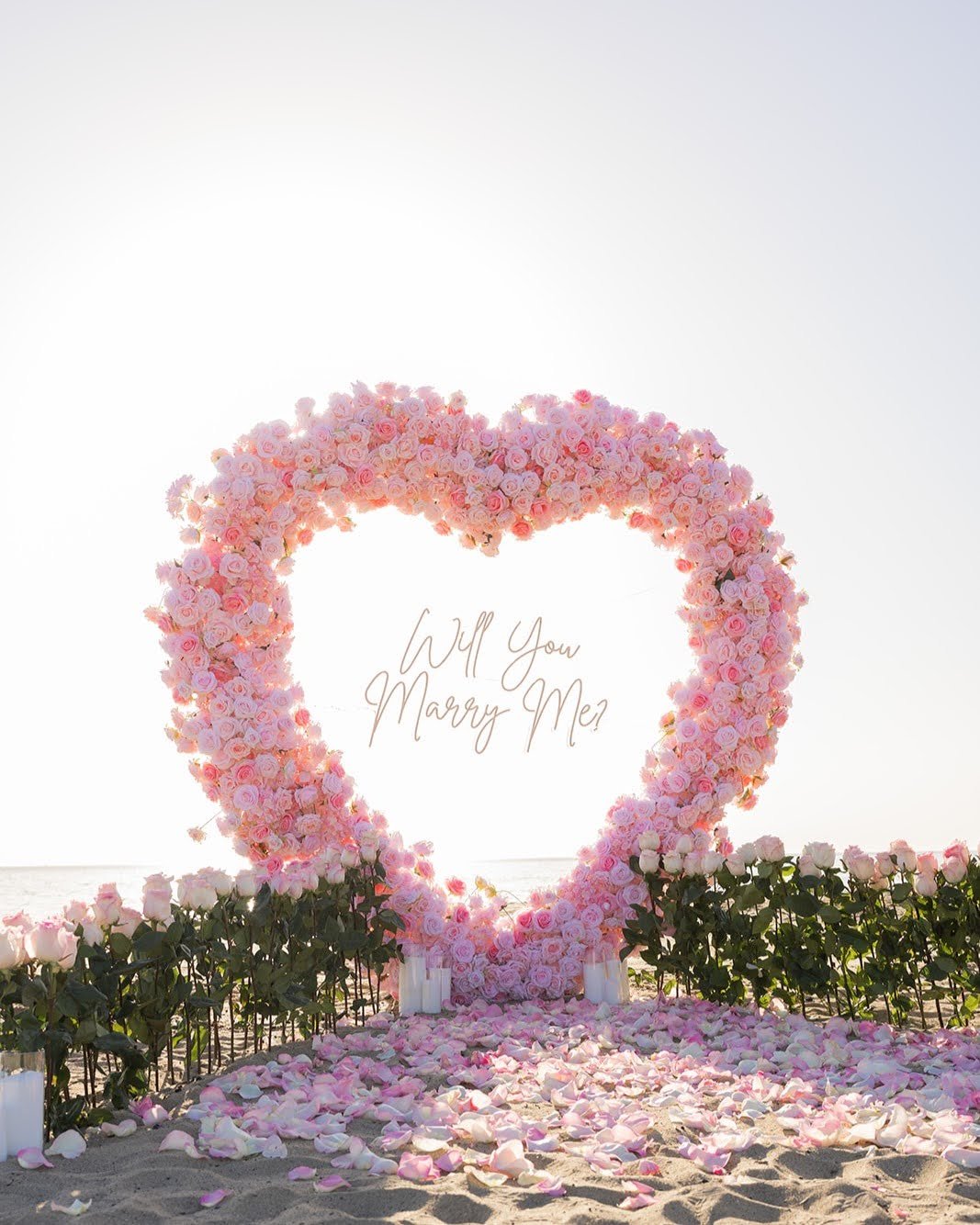 A pink floral proposal installation by the ocean