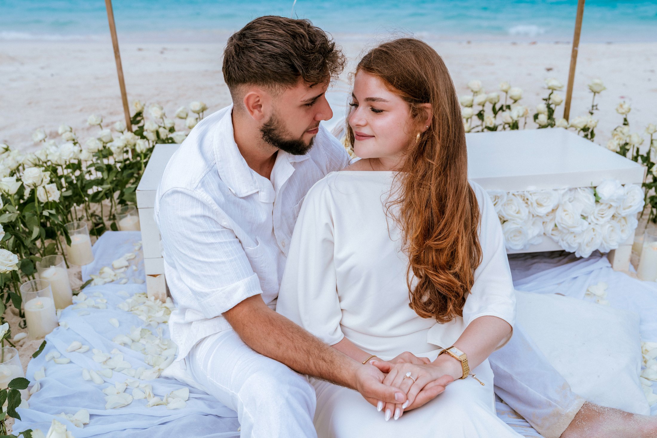 A couple seated together at an intimate beach proposal