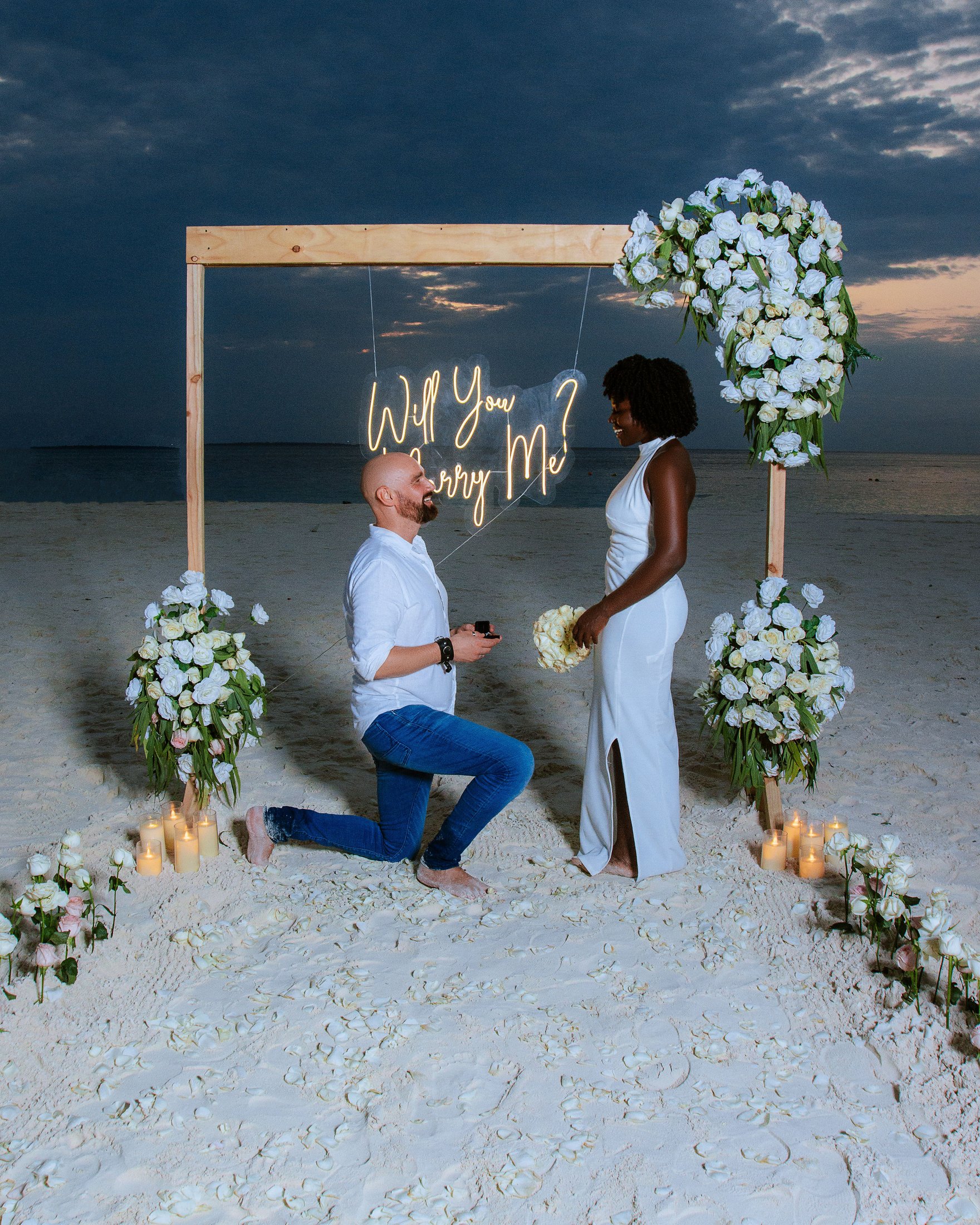 A sunset proposal beneath a softly lit floral frame